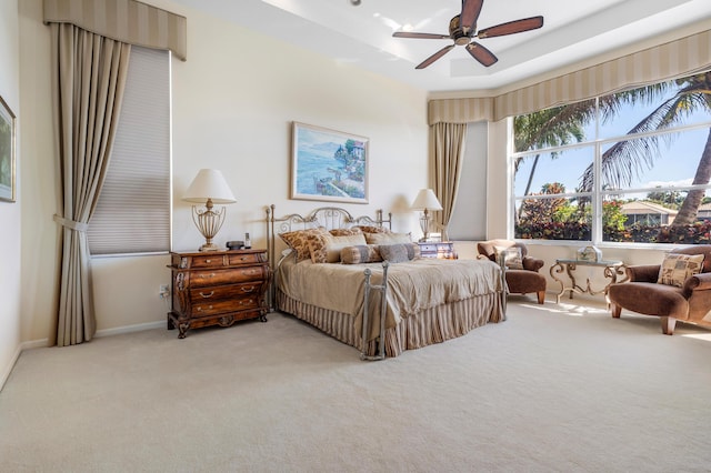 bedroom featuring baseboards, a tray ceiling, and light colored carpet