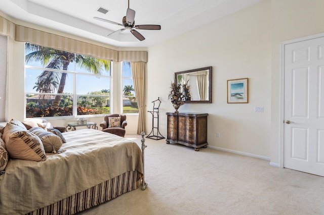 carpeted bedroom featuring visible vents, baseboards, a raised ceiling, and a ceiling fan