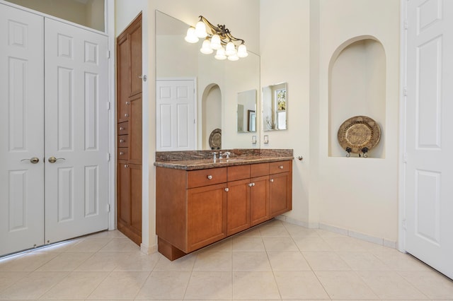 bathroom with a closet, tile patterned flooring, vanity, and baseboards