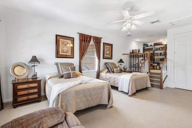 bedroom with a ceiling fan, attic access, visible vents, and light colored carpet