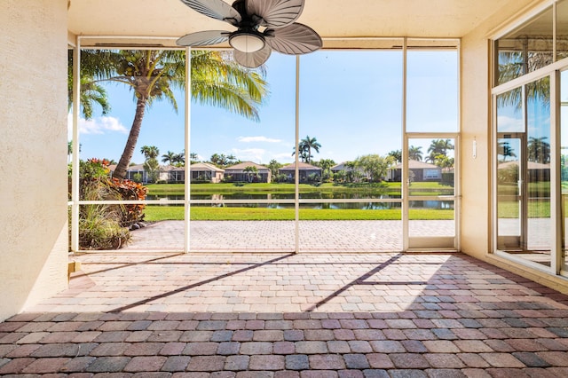 unfurnished sunroom featuring ceiling fan and a water view