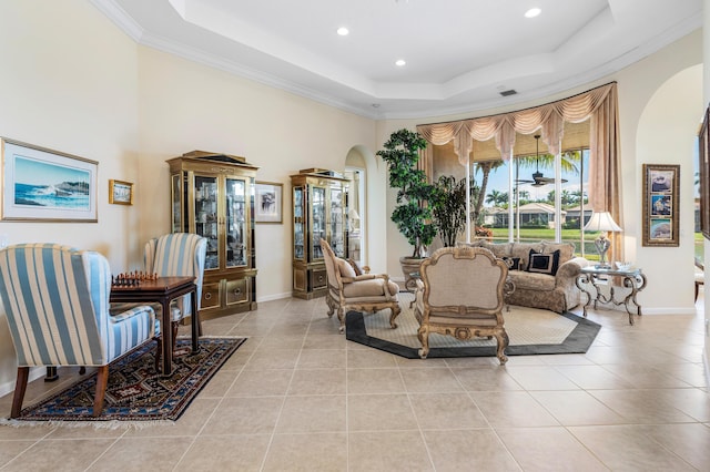 living room featuring arched walkways, baseboards, a tray ceiling, and light tile patterned floors