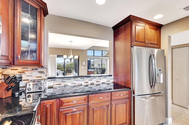 kitchen featuring tasteful backsplash, stainless steel fridge with ice dispenser, glass insert cabinets, dark stone countertops, and a notable chandelier