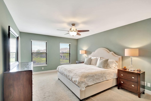 bedroom featuring light carpet, a ceiling fan, and baseboards