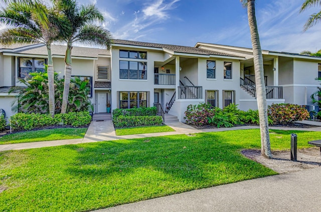 multi unit property with a front yard, stairway, and stucco siding