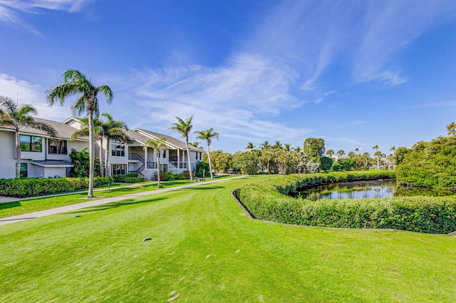 surrounding community with a water view and a lawn