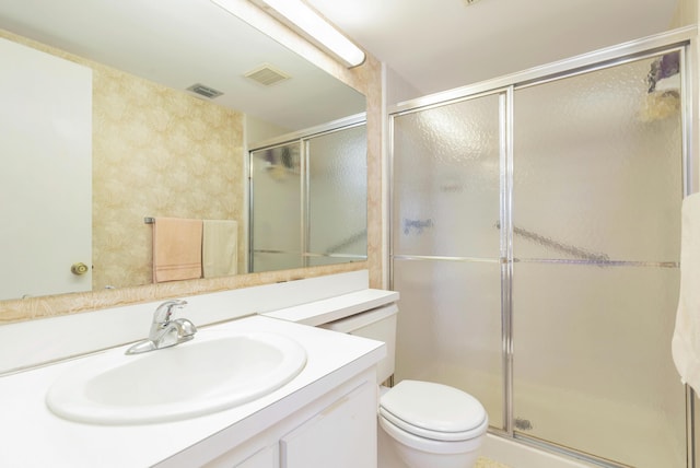 bathroom featuring vanity, an enclosed shower, and toilet