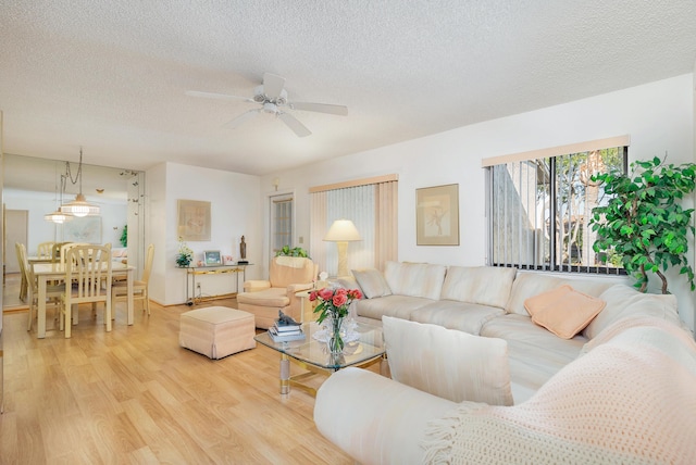 living room with ceiling fan, hardwood / wood-style flooring, and a textured ceiling