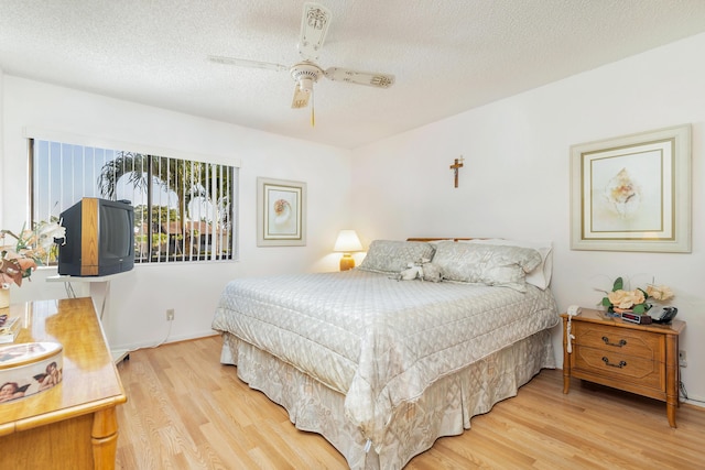 bedroom with ceiling fan, hardwood / wood-style floors, and a textured ceiling