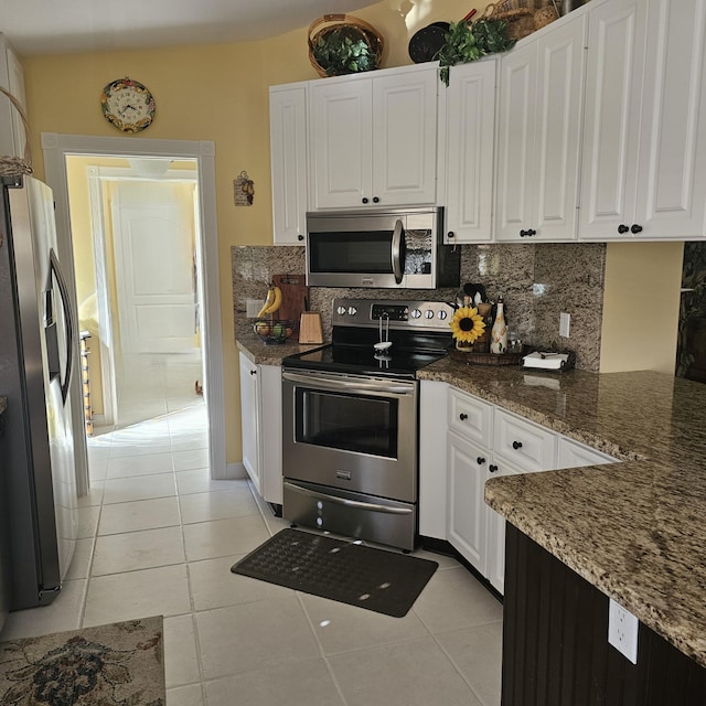 kitchen with appliances with stainless steel finishes, light tile patterned floors, white cabinetry, and tasteful backsplash