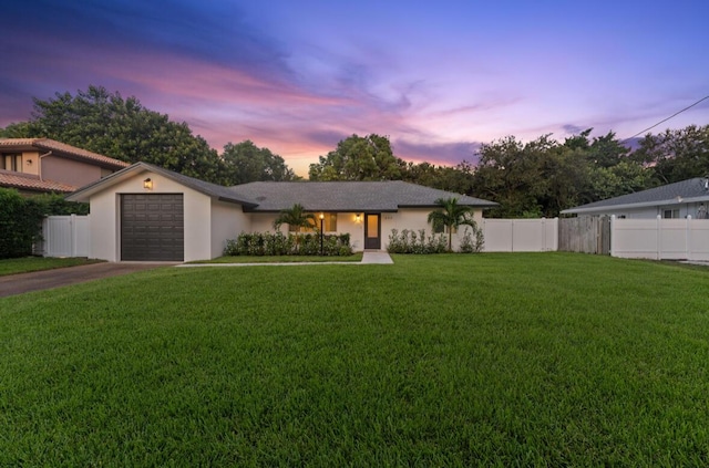 single story home featuring a garage and a lawn