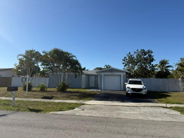 ranch-style house with concrete driveway, an attached garage, and fence