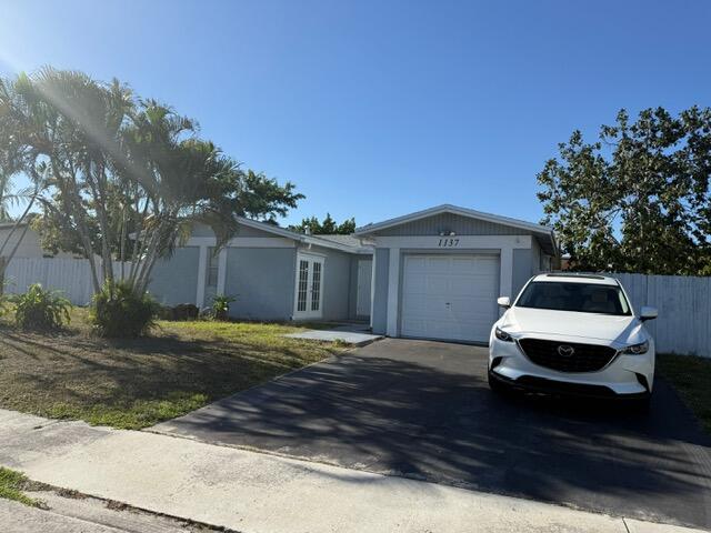 view of front facade with french doors, concrete driveway, an attached garage, and fence