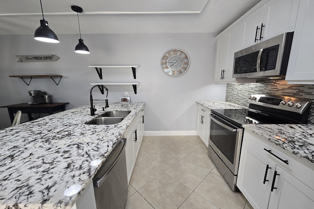 kitchen featuring hanging light fixtures, stainless steel appliances, light stone countertops, sink, and white cabinetry