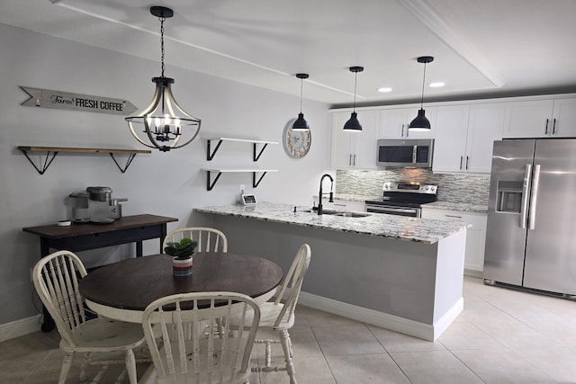 kitchen with white cabinets, appliances with stainless steel finishes, light stone countertops, and decorative light fixtures