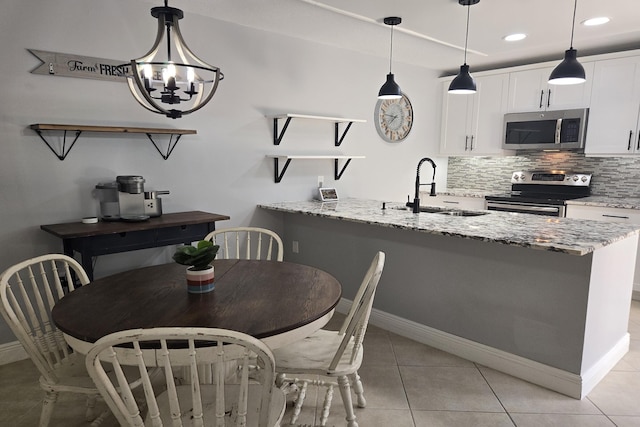 kitchen with appliances with stainless steel finishes, sink, light stone counters, decorative light fixtures, and white cabinets