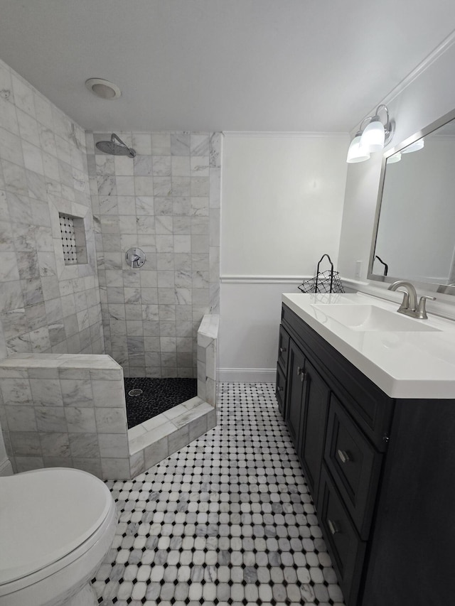 bathroom with tiled shower, vanity, toilet, and ornamental molding