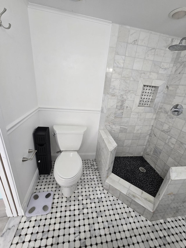 bathroom with tile patterned flooring, tiled shower, and toilet