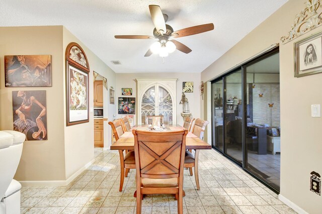 tiled dining area featuring a textured ceiling and ceiling fan