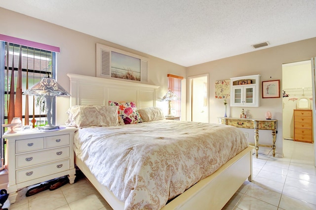 bedroom with a textured ceiling and light tile patterned floors