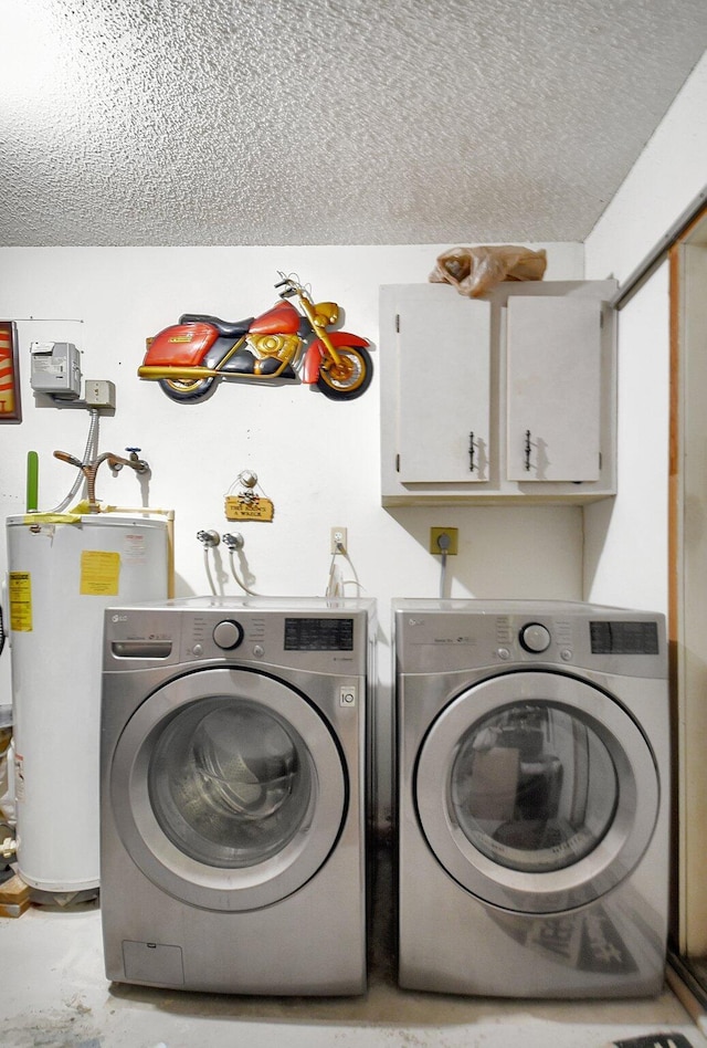 washroom with gas water heater, washing machine and dryer, cabinets, and a textured ceiling