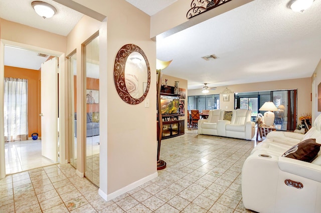tiled living room featuring ceiling fan and a textured ceiling
