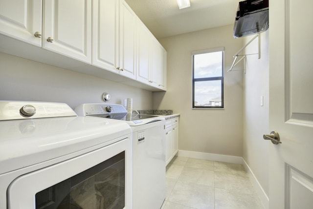 clothes washing area featuring washing machine and dryer, cabinets, and light tile patterned flooring