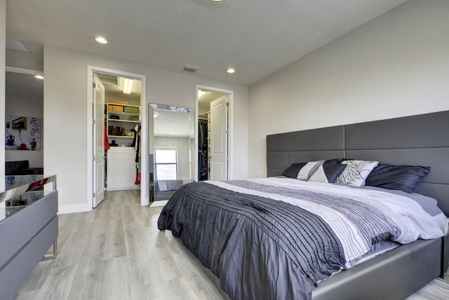 bedroom with a closet, a walk in closet, and light hardwood / wood-style flooring