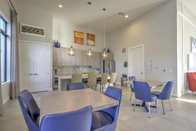 dining room featuring a high ceiling, light tile patterned flooring, and sink