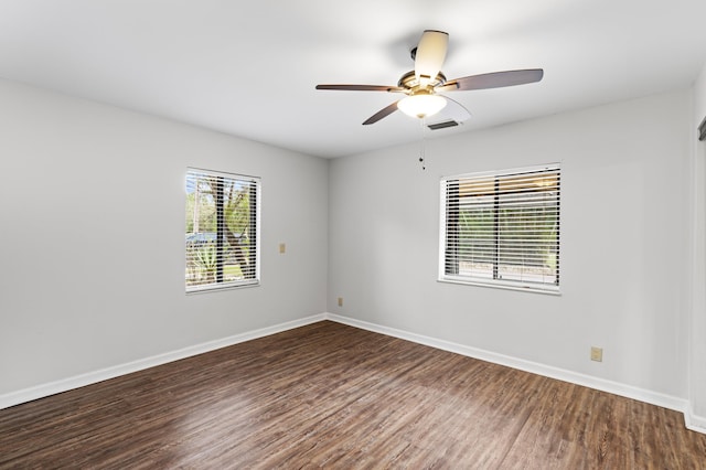 empty room with a wealth of natural light, ceiling fan, and dark hardwood / wood-style floors