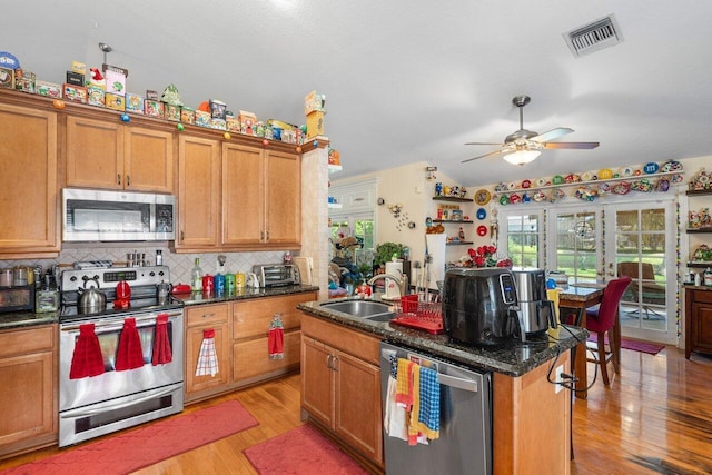 kitchen with light hardwood / wood-style flooring, appliances with stainless steel finishes, sink, a kitchen island with sink, and tasteful backsplash