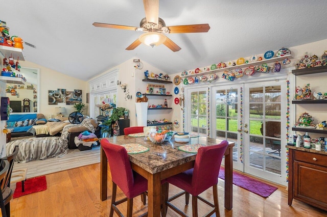 dining area featuring light wood-type flooring, french doors, vaulted ceiling, and a textured ceiling