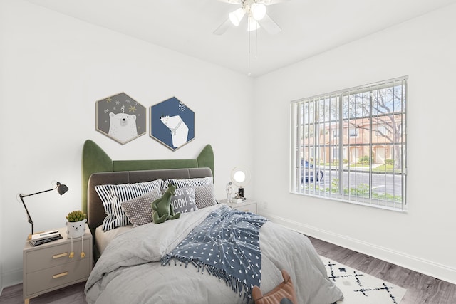 bedroom with multiple windows, wood finished floors, a ceiling fan, and baseboards