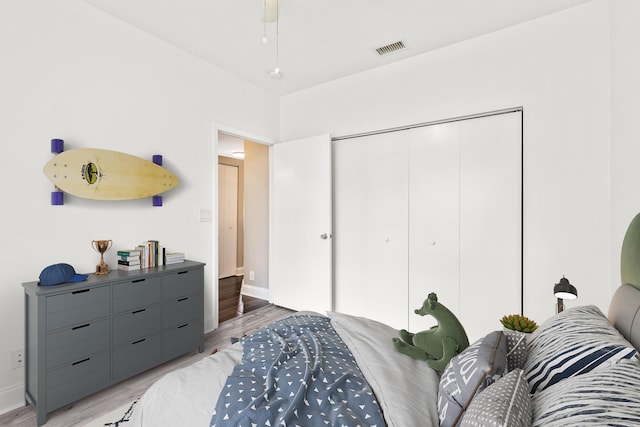 bedroom featuring a closet, light wood-type flooring, visible vents, and baseboards