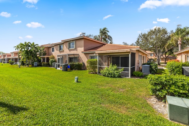 rear view of property featuring a sunroom, a lawn, and stucco siding