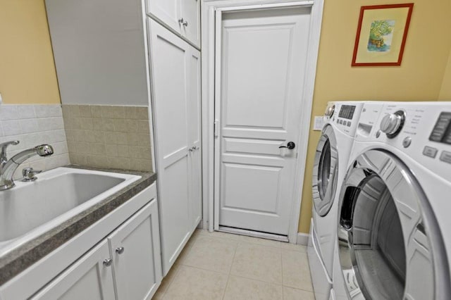 clothes washing area featuring cabinets, sink, light tile patterned floors, and washing machine and clothes dryer