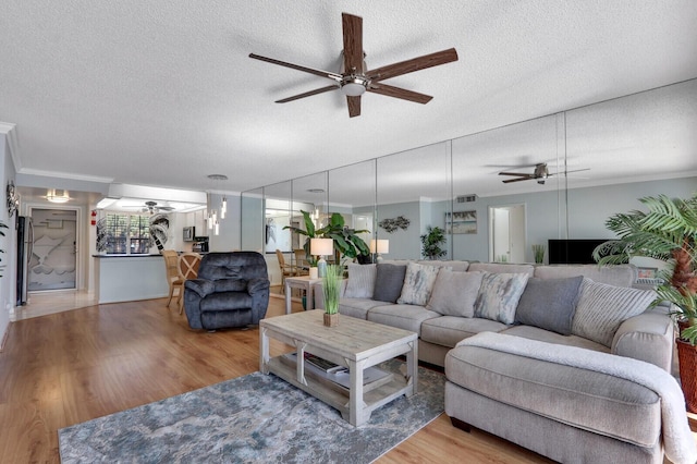 living room featuring ornamental molding, ceiling fan, a textured ceiling, and hardwood / wood-style floors