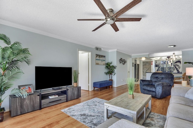 living room featuring ceiling fan, wood-type flooring, a textured ceiling, and crown molding