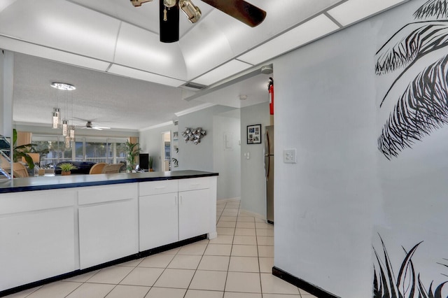 kitchen featuring light tile patterned floors, ceiling fan, white cabinets, stainless steel refrigerator, and ornamental molding