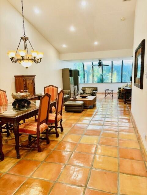 dining room with light tile patterned floors, ceiling fan with notable chandelier, recessed lighting, and high vaulted ceiling