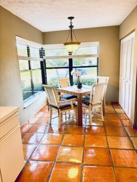 dining room with light tile patterned floors, a textured ceiling, and baseboards