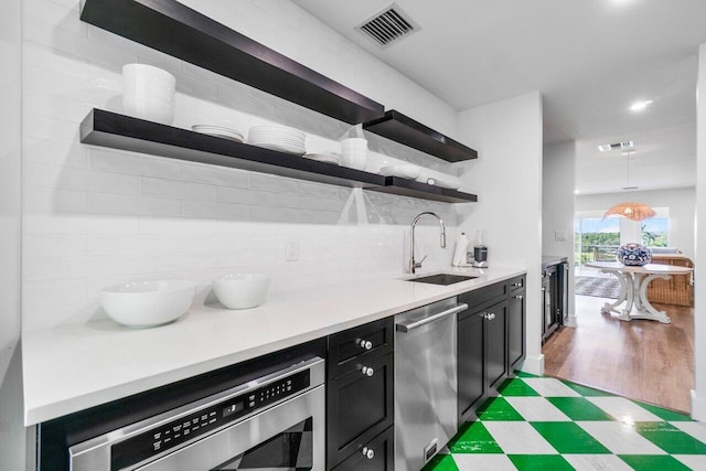 kitchen with open shelves, light countertops, visible vents, stainless steel dishwasher, and dark cabinetry