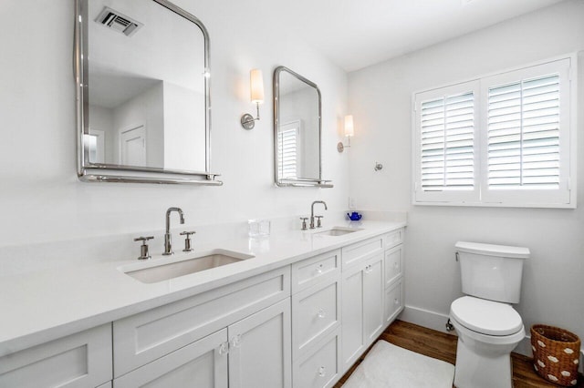 full bathroom featuring double vanity, visible vents, toilet, and a sink