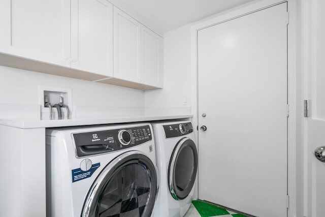 clothes washing area with washing machine and dryer and cabinet space