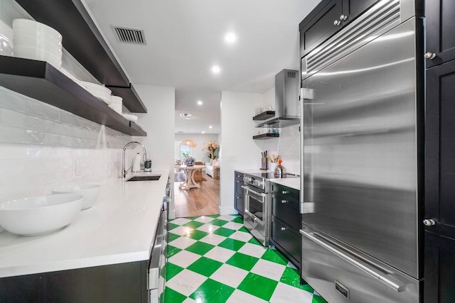 kitchen with open shelves, high end appliances, light countertops, visible vents, and a sink