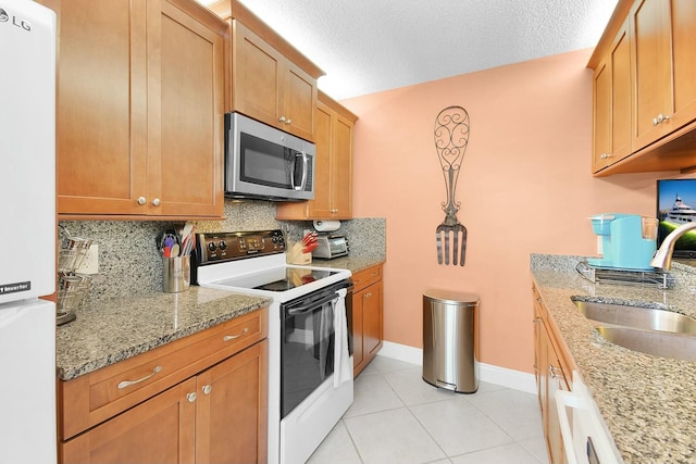 kitchen with tasteful backsplash, white appliances, light stone countertops, and sink