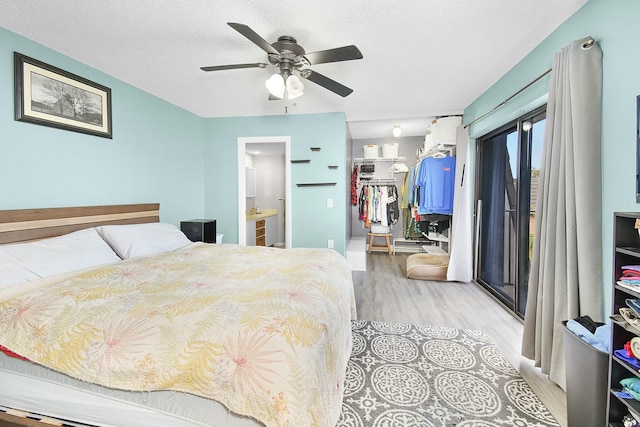 bedroom featuring light hardwood / wood-style flooring, connected bathroom, a textured ceiling, a spacious closet, and a closet