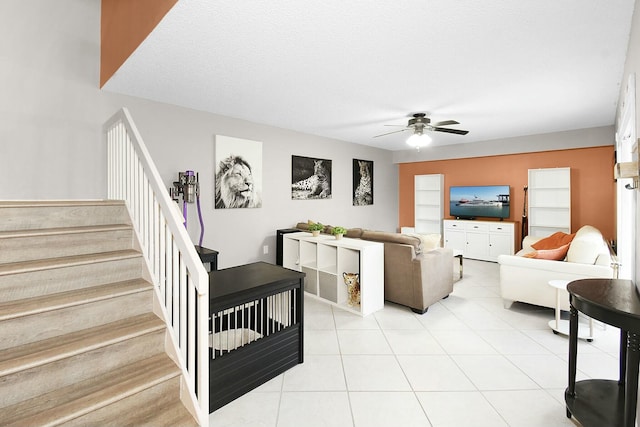 tiled living room featuring built in shelves, ceiling fan, and a textured ceiling