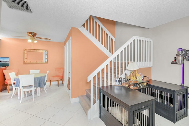 stairway featuring ceiling fan, tile patterned floors, and a textured ceiling