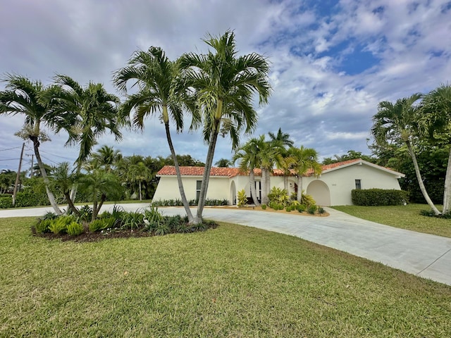 mediterranean / spanish-style house with stucco siding, a tiled roof, concrete driveway, and a front yard